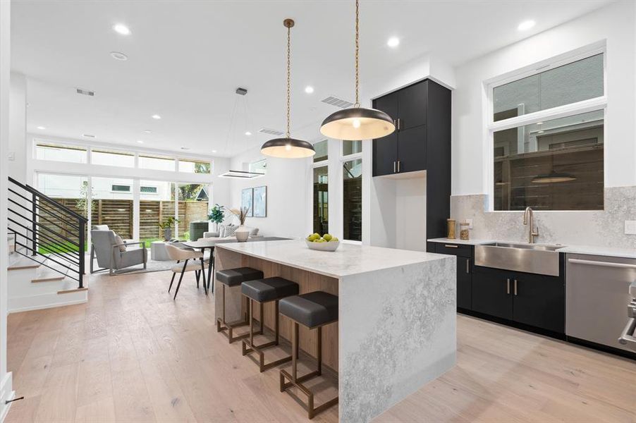 Kitchen design includes quartz waterfall island, engineered white oak hardwood floors and dry bar.