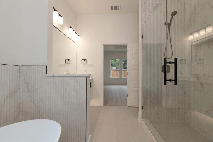 Bathroom featuring a shower stall, a freestanding tub, vanity, and light tile patterned floors