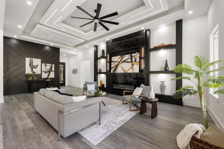 Spacious living area featuring a multi-tiered tray ceiling with integrated lighting, a contemporary ceiling fan, and recessed lighting