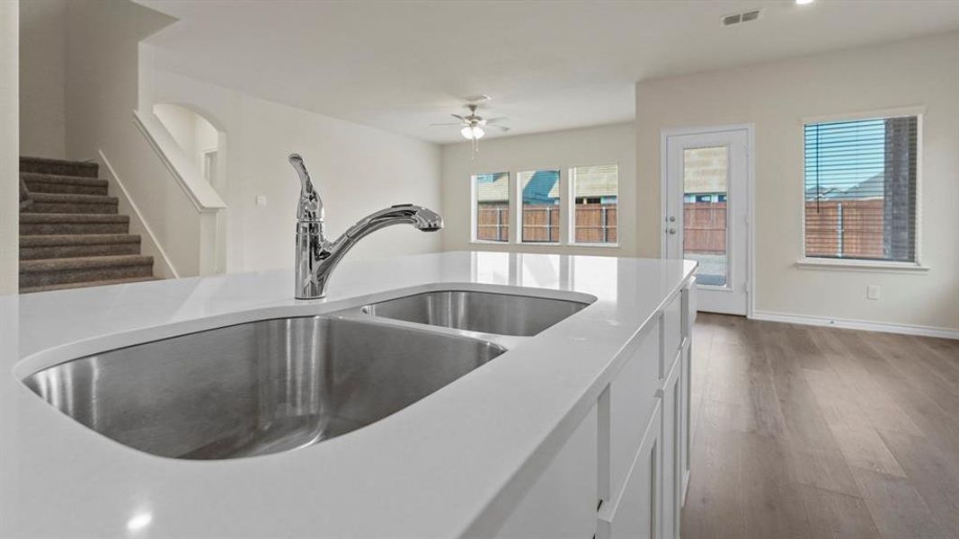 Kitchen featuring white cabinetry, wood finished floors, light stone countertops, ceiling fan, and recessed lighting Kitchen featuring white cabinetry, wood finished floors, light stone countertops, ceiling fan, and recessed lighting