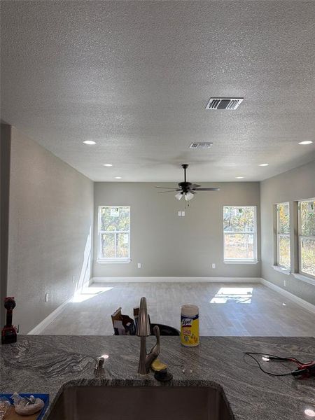 Kitchen featuring open floor plan, wood finished floors, dark stone countertops, a textured ceiling, and ceiling fan Kitchen featuring open floor plan, wood finished floors, dark stone countertops, a textured ceiling, and ceiling fan