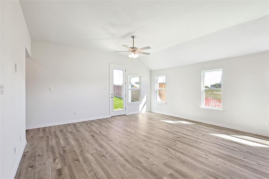 Spare room featuring light wood-type flooring, vaulted ceiling, and ceiling fan