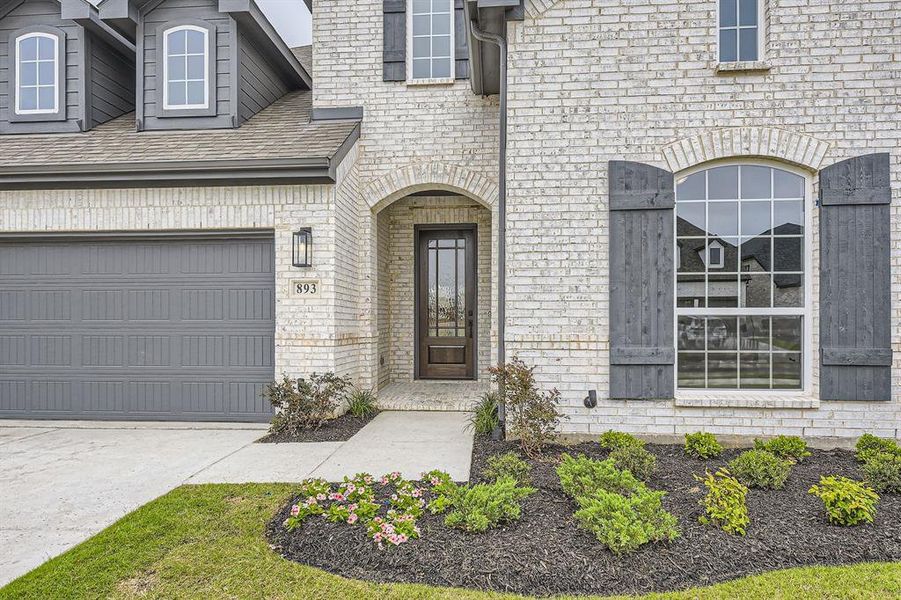 Entrance to property featuring driveway, brick siding, and roof with shingles