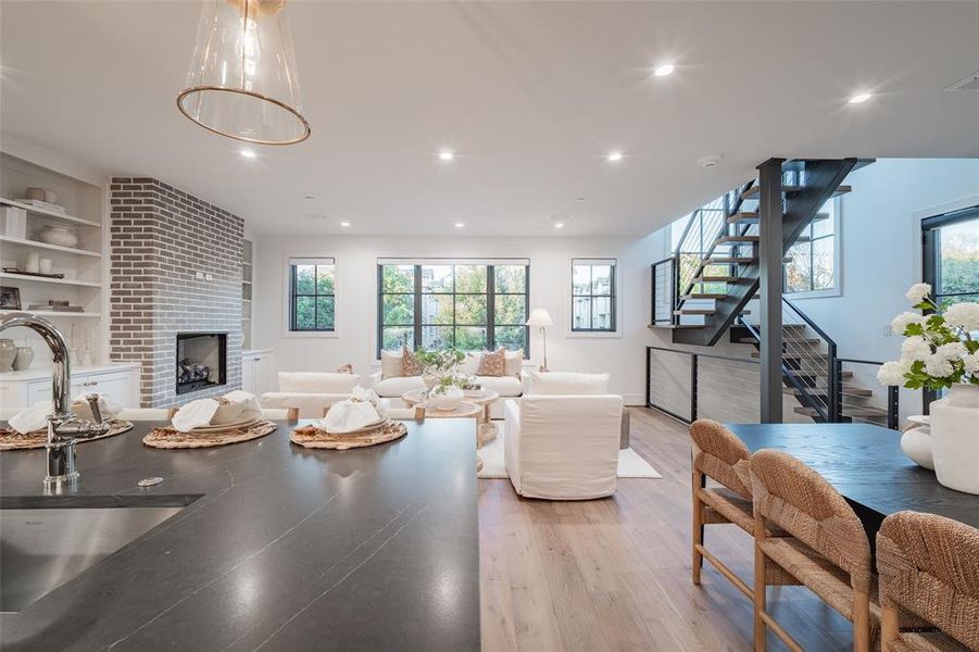 Living room featuring a fireplace, built in shelves, light hardwood / wood-style floors, and sink