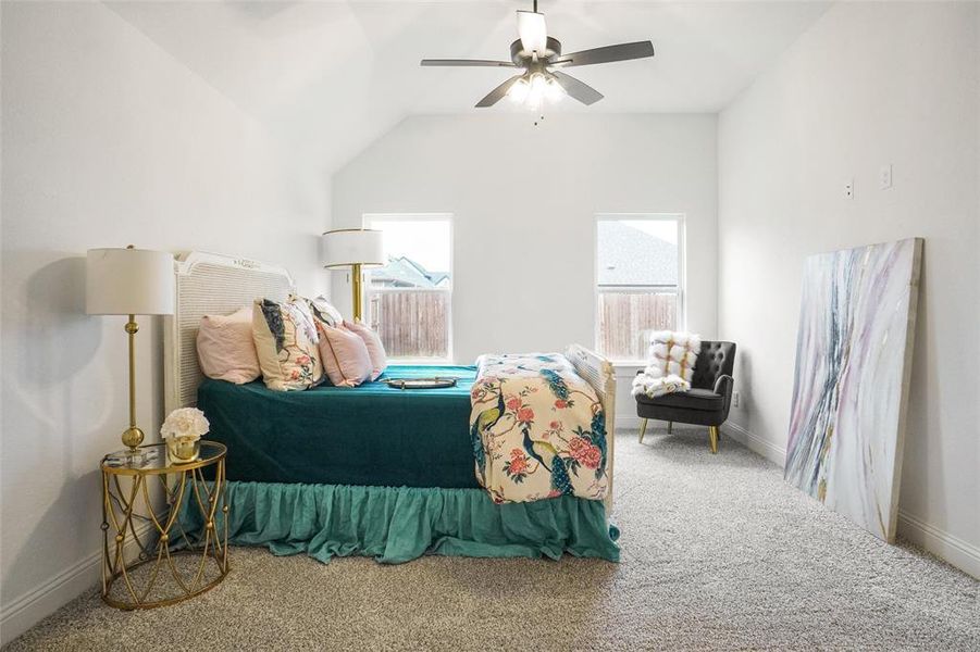 Bedroom with vaulted ceiling, ceiling fan, and carpet floors