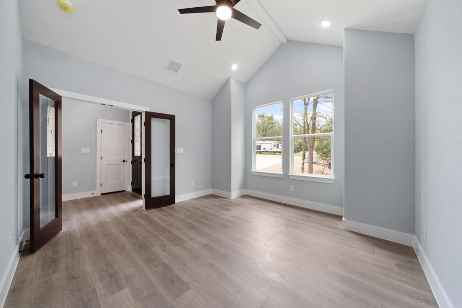 Vaulted ceiling room featuring wood-finish flooring, two large windows, recessed lighting, and a ceiling fan