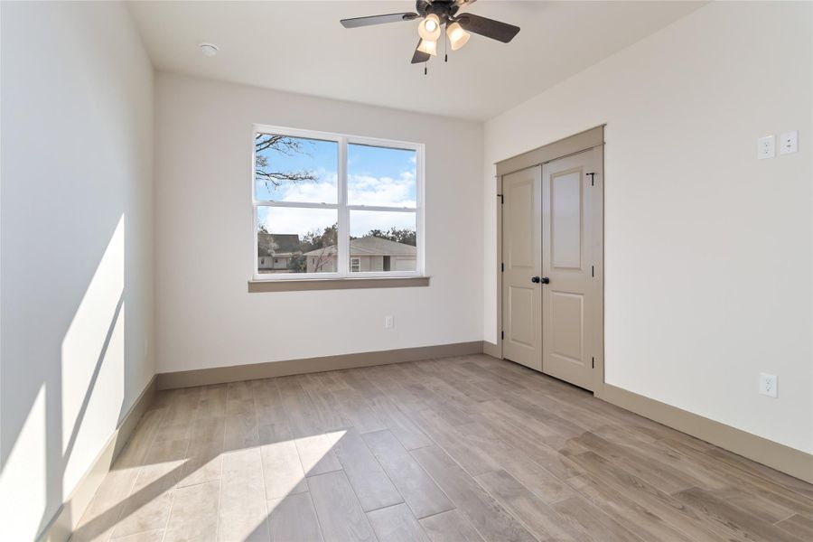Bedroom #2 - Front-facing secondary bedroom. Closet doors visible - without virtual staging