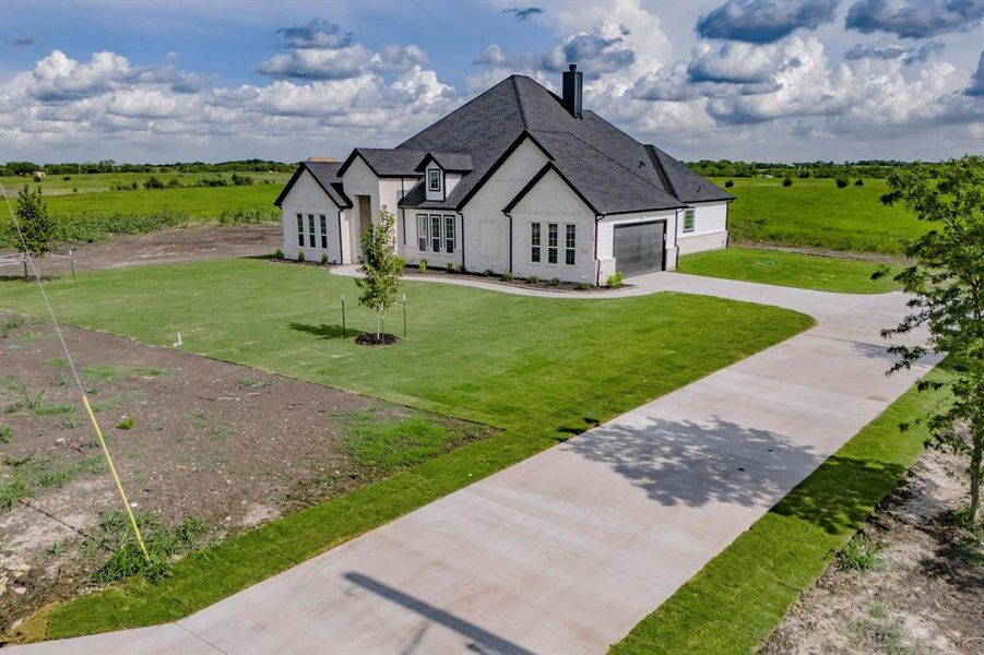 View of front of house featuring a garage, a rural view, and a front yard