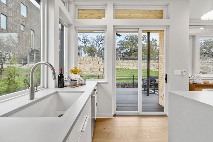 Doorway with light wood finished floors, plenty of natural light, a sink, and baseboards