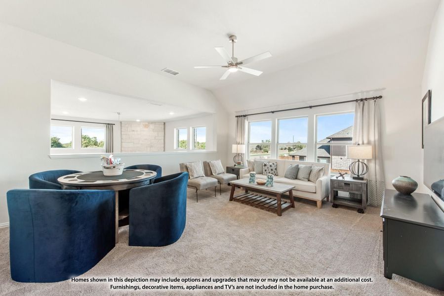 Open living room with vaulted ceiling, ceiling fan, carpet floors, and large windows with natural light