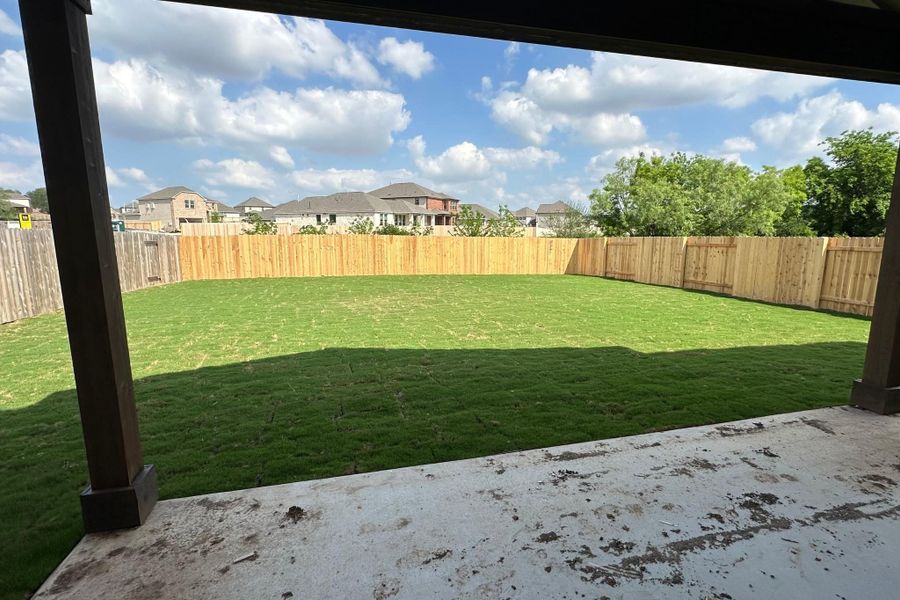 Expansive backyard featuring a manicured lawn, full privacy fencing, and a concrete patio