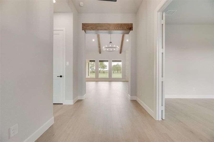 Corridor featuring light wood-style flooring, a chandelier, beam ceiling, and recessed lighting