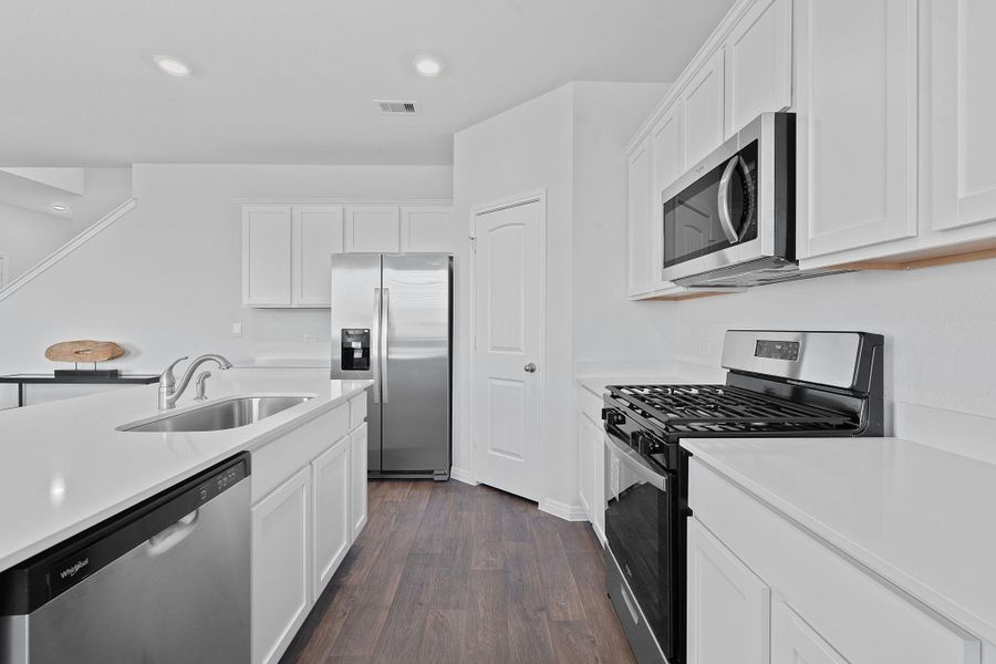 Kitchen with stainless steel appliances, white cabinets, dark wood-type flooring, recessed lighting, and light stone counters Kitchen with stainless steel appliances, white cabinets, dark wood-type flooring, recessed lighting, and light stone counters