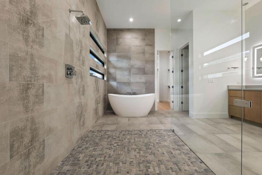 Spacious bathroom featuring a frameless glass shower enclosure, a freestanding soaking tub, and a vanity with a quartz countertop
