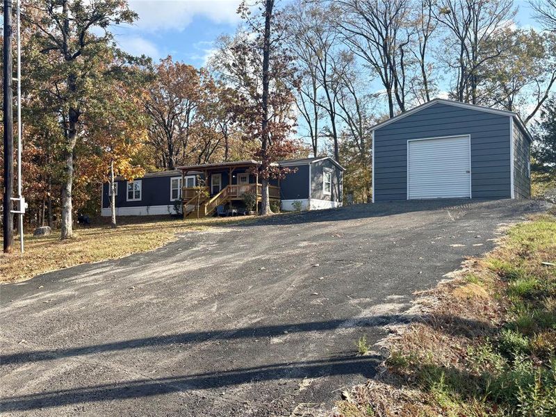 View of front of home featuring an outdoor structure, a garage, and asphalt driveway