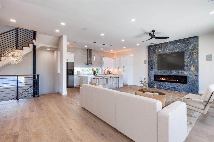 Living room with light hardwood / wood-style floors, a fireplace, sink, and ceiling fan