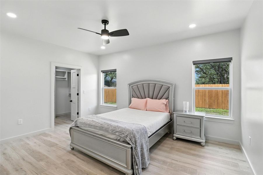 Bedroom featuring light wood-style flooring, a walk in closet, ceiling fan, and recessed lighting