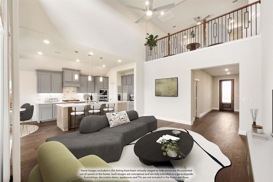 Open-concept living room with vaulted ceiling, hardwood floors, and kitchen visible in background with second-floor loft above Open-concept living room with vaulted ceiling, hardwood floors, and kitchen visible in background with second-floor loft above