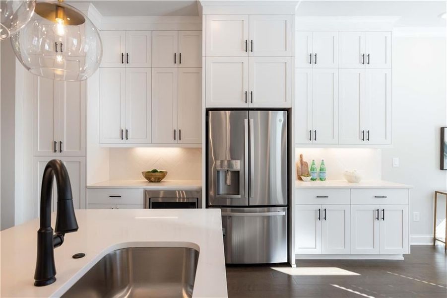 Kitchen with light countertops, stainless steel refrigerator with ice dispenser, a sink, and white cabinetry