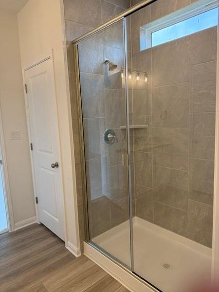 Walk-in shower featuring glass enclosure, tiled walls, built-in shelving, a transom window, and a rain showerhead