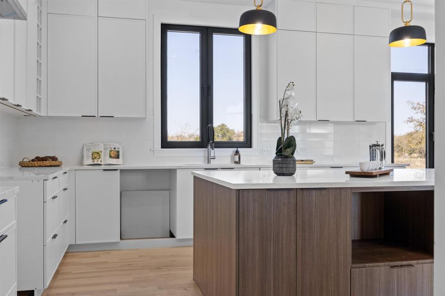 Kitchen featuring plenty of natural light, white cabinets, modern cabinets, and light countertops