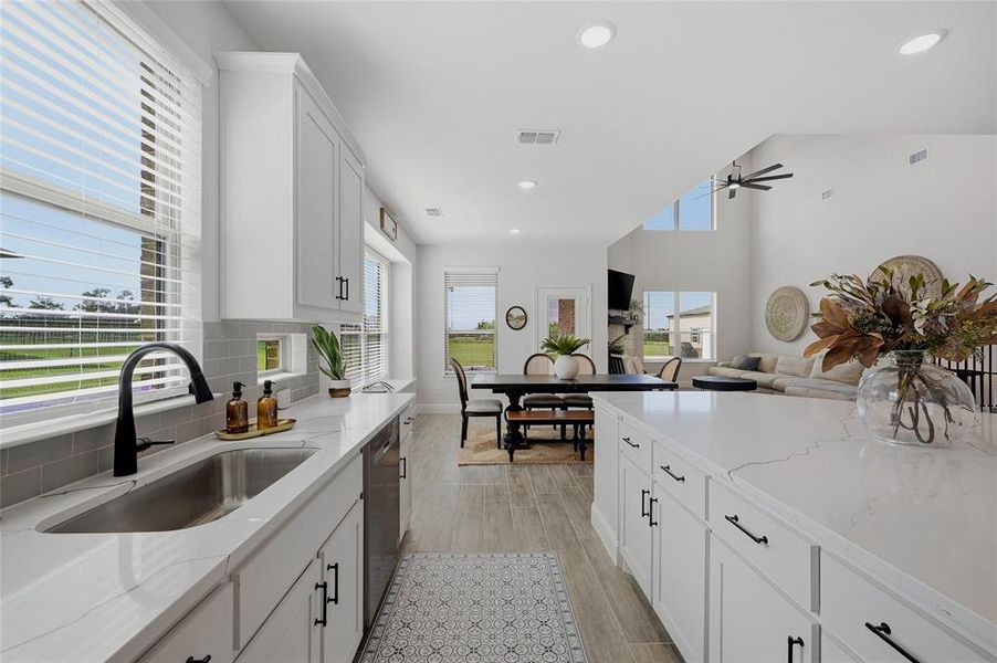 Modern kitchen featuring white shaker cabinetry, white countertops, a stainless steel undermount sink with a black gooseneck faucet, and light grey subway tile backsplash