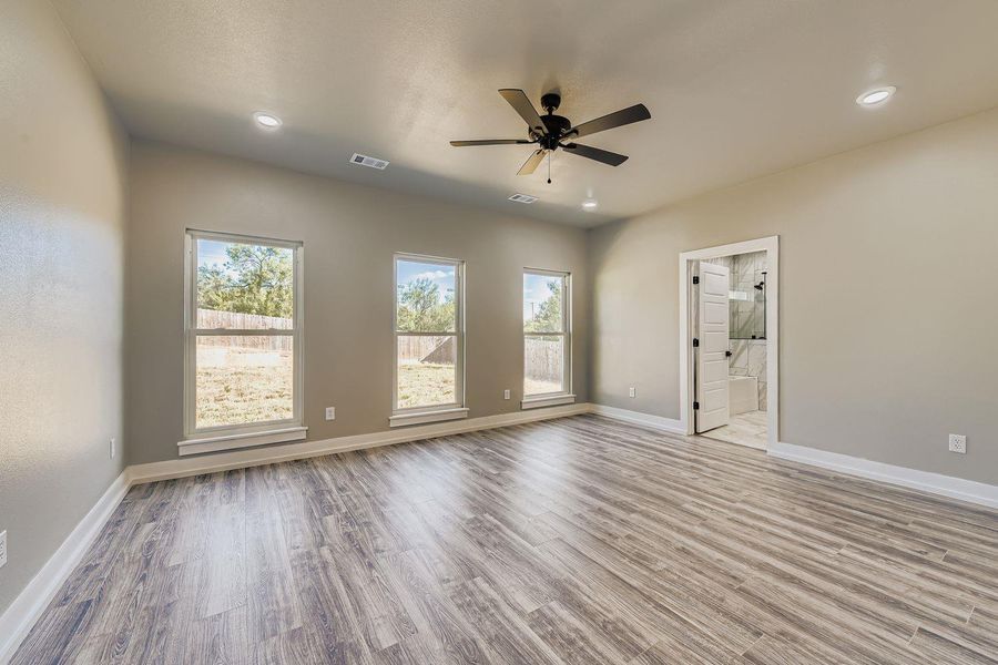 Unfurnished bedroom featuring light wood-type flooring, ceiling fan, connected bathroom, and recessed lighting