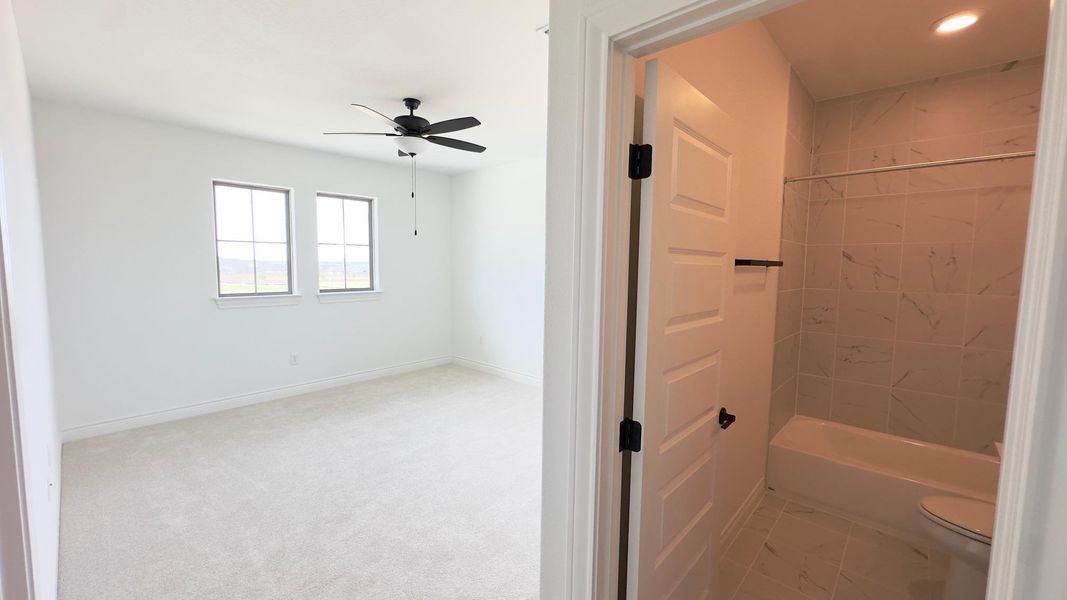 Bathroom featuring shower / tub combination, ceiling fan, and light colored carpet