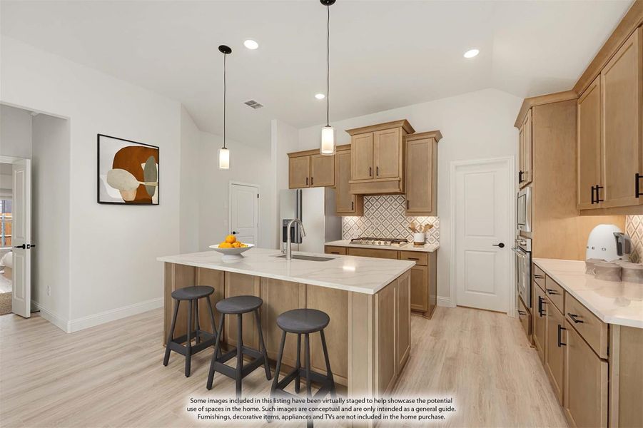 Kitchen with large center island, light wood cabinets, quartz countertops, and three bar stools on light hardwood floors