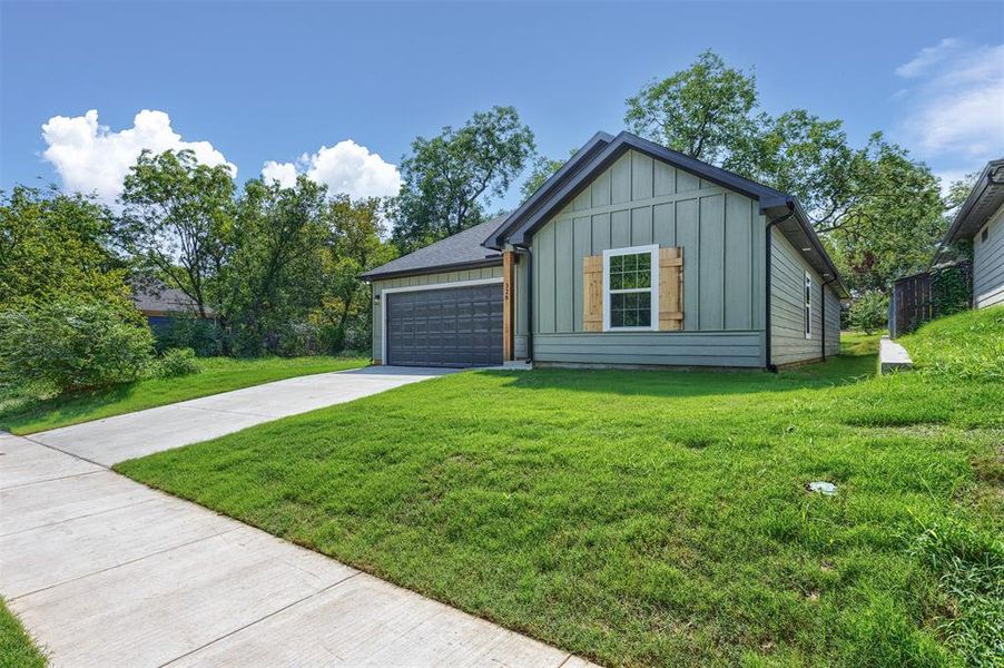 View of front facade featuring board and batten siding, concrete driveway, a front lawn, and a garage View of front facade featuring board and batten siding, concrete driveway, a front lawn, and a garage