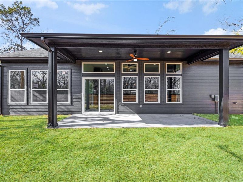 Rear view of property with a ceiling fan, a patio area, and a yard
