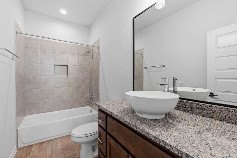 Modern bath features a vessel sink atop granite counters and a tiled tub-shower combination. Modern bath features a vessel sink atop granite counters and a tiled tub-shower combination.