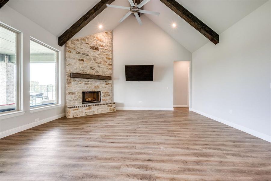 Unfurnished living room with beam ceiling, hardwood / wood-style floors, high vaulted ceiling, and ceiling fan