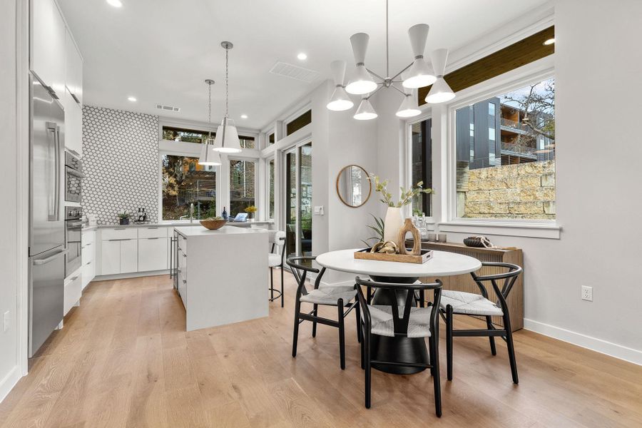 Dining space with light wood finished floors, recessed lighting, visible vents, and baseboards