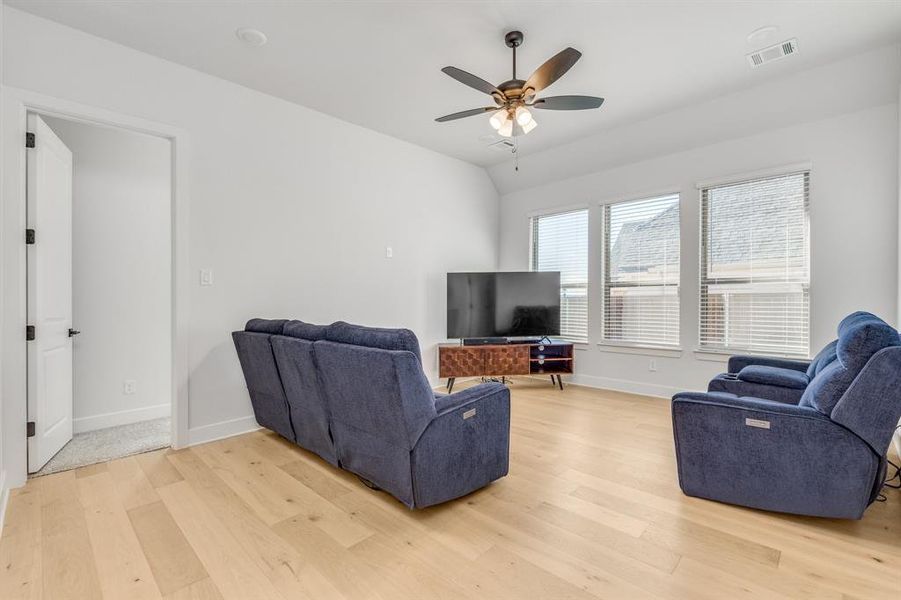 Living room featuring ceiling fan, lofted ceiling, and light wood-type flooring