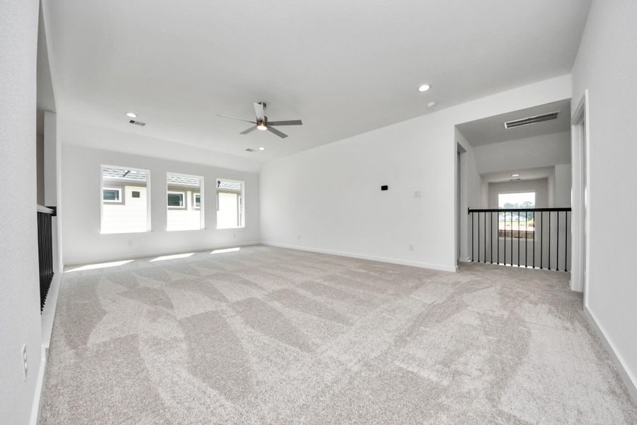 Come upstairs and enjoy a day of leisure in this fabulous game room! This is the perfect hangout spot or adult game room! Features plush carpet, high ceilings, custom paint and windows for plenty of natural light. Sample photo of completed home with similar floor plan. Actual colors and selections may vary.