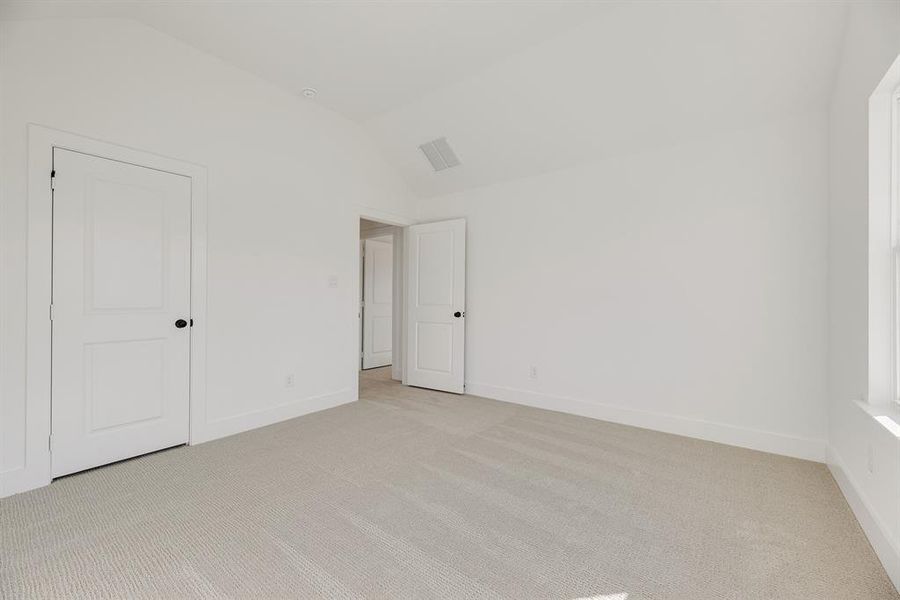 Unfurnished bedroom with vaulted ceiling and carpet