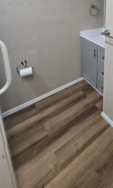 Detailed view of bathroom with walk-in tub, vanity, a textured wall, and wood finished vinyl floors.