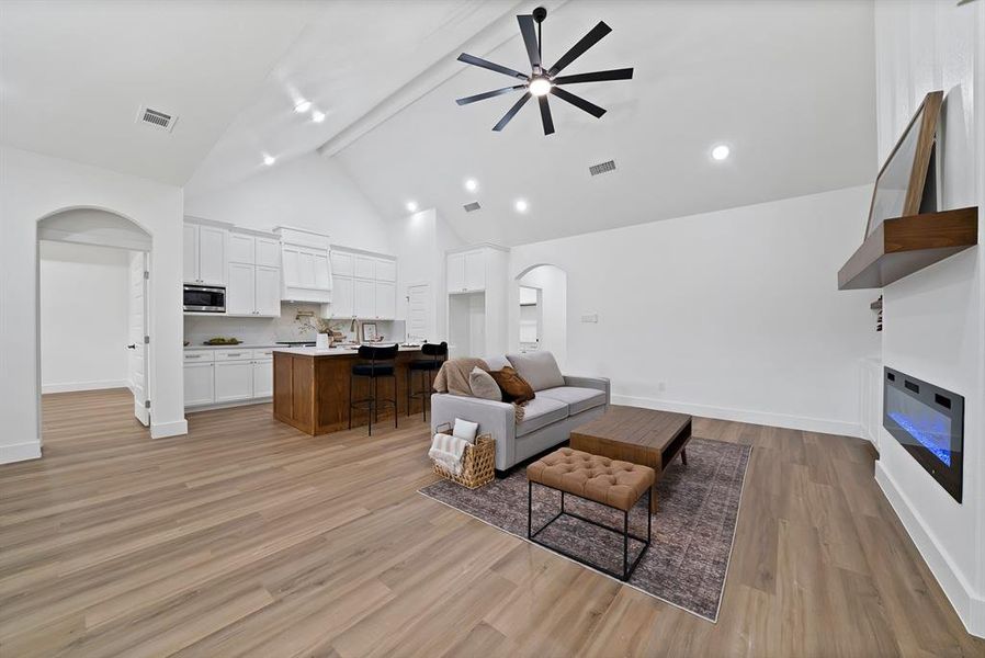 Open-concept living area featuring high vaulted ceilings with a contemporary ceiling fan, wood-finish flooring, and recessed lighting Open-concept living area featuring high vaulted ceilings with a contemporary ceiling fan, wood-finish flooring, and recessed lighting