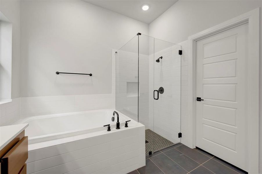 Bathroom featuring vanity, a garden tub, a stall shower, and dark tile patterned flooring