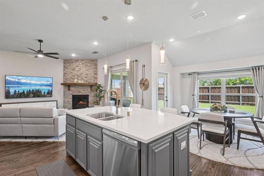 Kitchen featuring stainless steel dishwasher, gray cabinetry, a fireplace, dark wood-style flooring, and vaulted ceiling Kitchen featuring stainless steel dishwasher, gray cabinetry, a fireplace, dark wood-style flooring, and vaulted ceiling