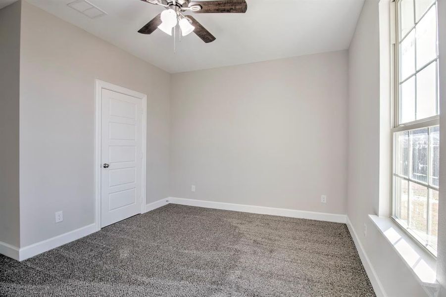 Carpeted spare room with healthy amount of natural light and ceiling fan