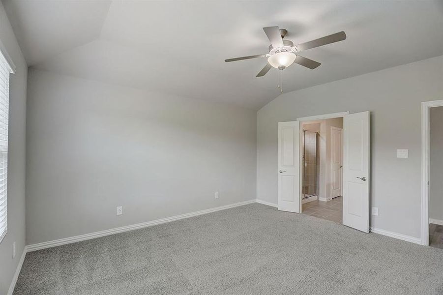 Unfurnished bedroom featuring vaulted ceiling, light carpet, and ceiling fan