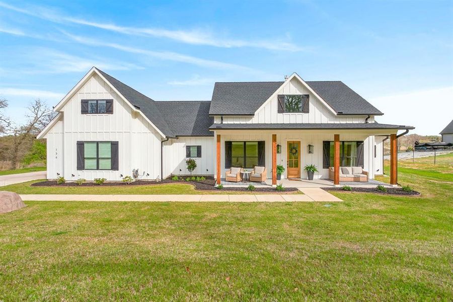 Modern farmhouse style home featuring board and batten siding, a porch, a shingled roof, and a front lawn Modern farmhouse style home featuring board and batten siding, a porch, a shingled roof, and a front lawn