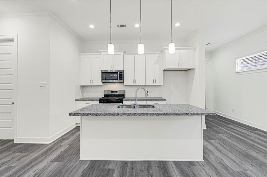 Modern kitchen with sleek white cabinetry, granite countertops, and stainless steel appliances. The open layout features a central island with a sink and pendant lighting, complemented by stylish gray flooring. Modern kitchen with sleek white cabinetry, granite countertops, and stainless steel appliances. The open layout features a central island with a sink and pendant lighting, complemented by stylish gray flooring.