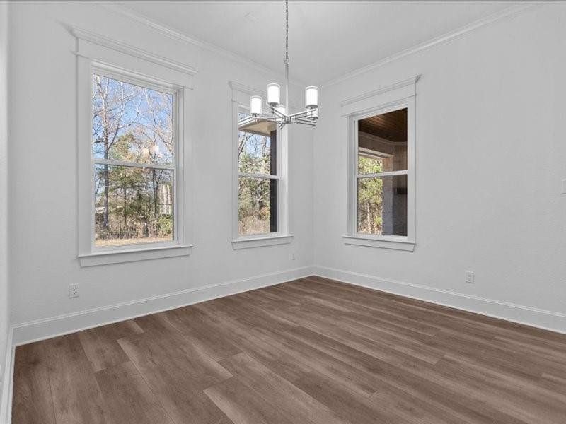 Unfurnished dining area featuring a chandelier, dark wood-style floors, and crown molding