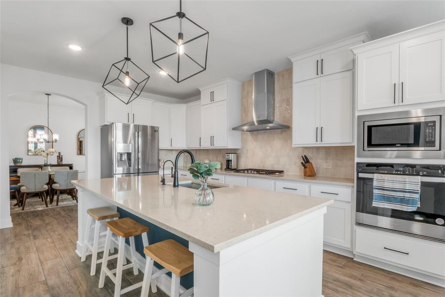 Kitchen featuring backsplash, pendant lighting, stainless steel appliances, a chandelier, and recessed lighting Kitchen featuring backsplash, pendant lighting, stainless steel appliances, a chandelier, and recessed lighting