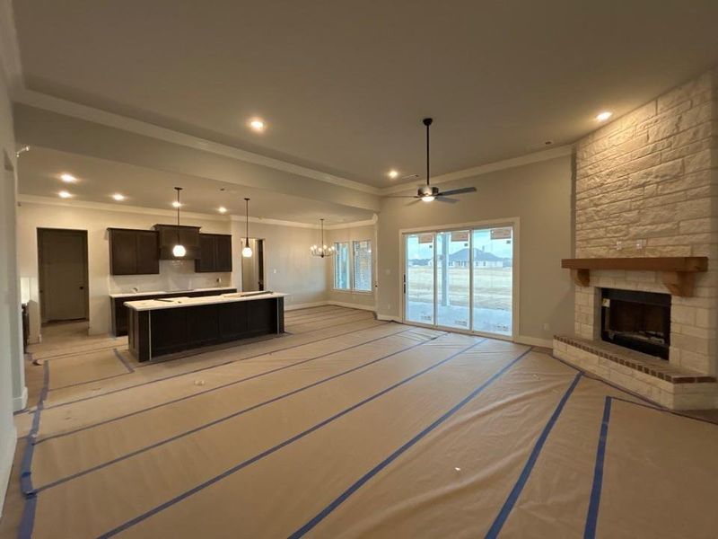 Unfurnished living room with a fireplace, a ceiling fan, crown molding, a chandelier, and recessed lighting