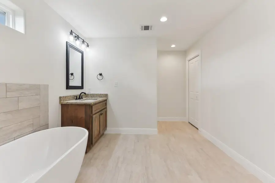 Full bath with wood finished floors, vanity, a soaking tub, visible vents, and recessed lighting