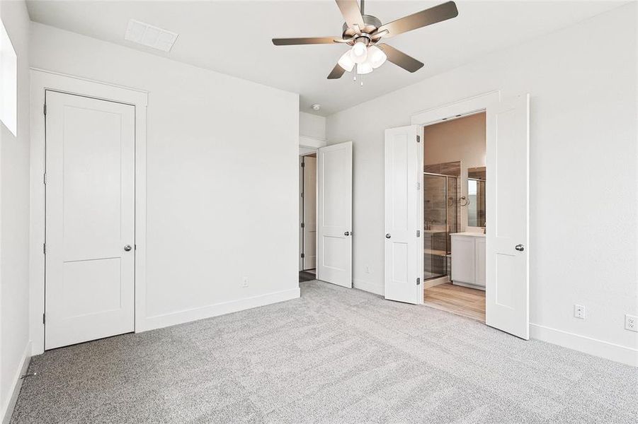 Unfurnished bedroom with ensuite bath, ceiling fan, and light colored carpet